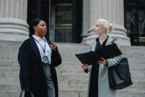 elegant diverse female business partners with documents talking on street